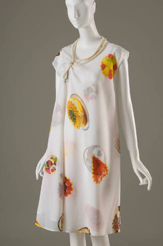 White sleeveless knee length dress printed with photographs of desserts and pastries and neckli…