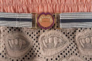 Detail of orange ruching, taupe lace with mouth and fang motif and striped belt with mouth with…