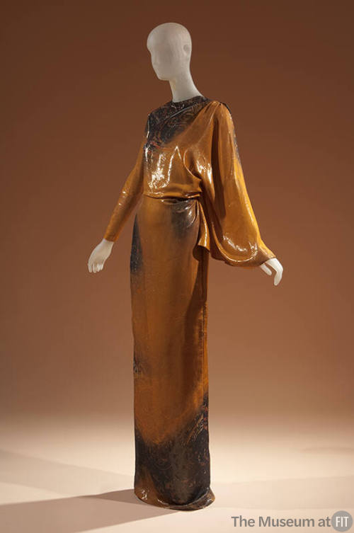 Shimmery orange and black abstract print floor length evening dress with one fitted sleeve and …