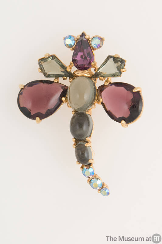 Dragonfly shaped pin of gold tone metal set with purple, grey and blue glass stones
