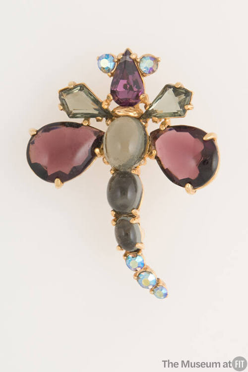 Dragonfly shaped pin of gold tone metal set with purple, grey and blue glass stones