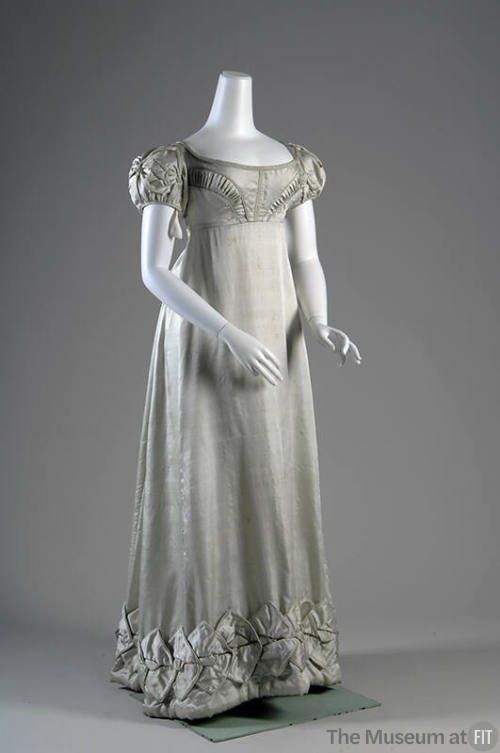 Pale aqua blue dress with pleated motifs on bodice above empire waist and folded motifs on shor…