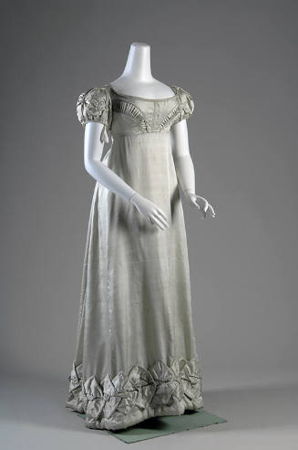 Pale aqua blue dress with pleated motifs on bodice above empire waist and folded motifs on shor…