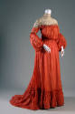 Red-orange dress with long sleeves puffed from elbow, cream lace yoke with band collar, blouson…
