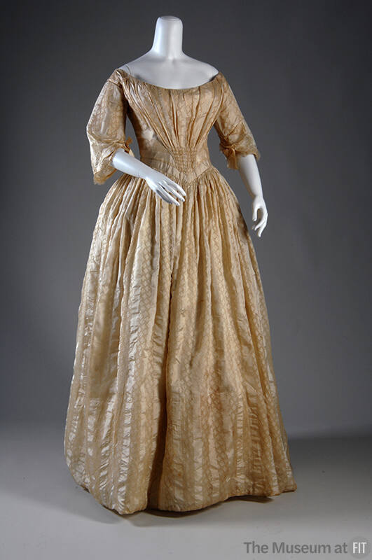 Ivory floor length dress with vertical patterned stripes, wide open neck, V-shaped pleating at …