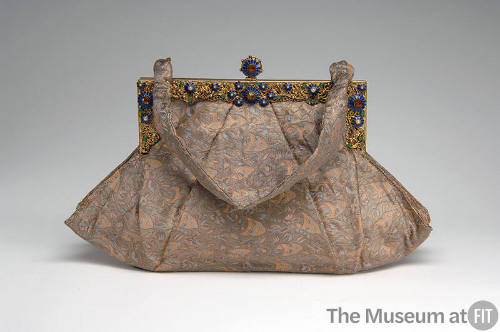 Beige and blue evening bag in theatrical mask pattern with jeweled gold metal frame and short h…