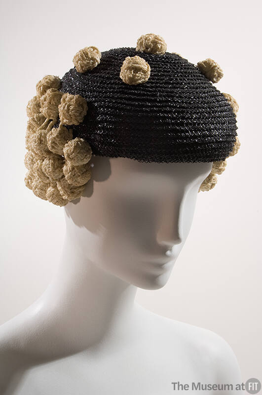 Shiny black straw beret with white straw knots forming side flaps and scattered across top