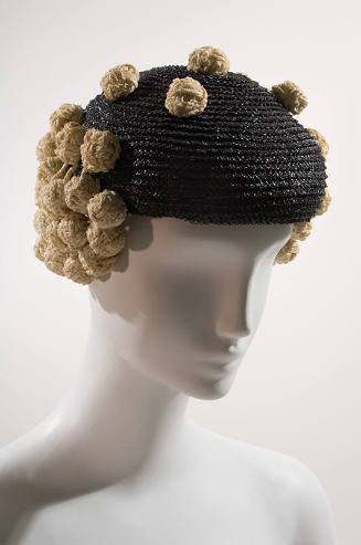 Shiny black straw beret with white straw knots forming side flaps and scattered across top