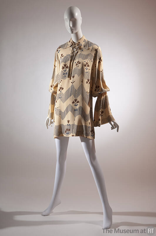Beige tunic with blue and brown flower and fence print; long sleeves with flared cuffs