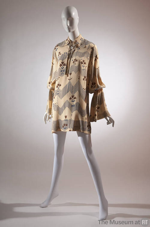 Beige tunic with blue and brown flower and fence print; long sleeves with flared cuffs