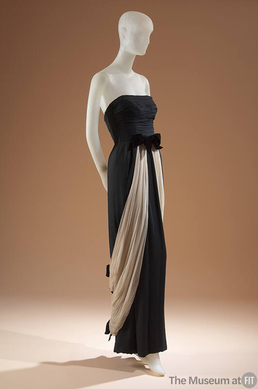 Black strapless floor length evening dress with cream silk gauze overskirt draping from bow at …
