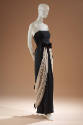 Black strapless floor length evening dress with cream silk gauze overskirt draping from bow at …