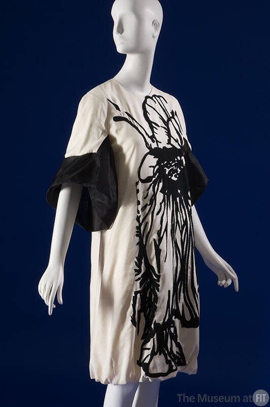 Off-white knee length dress with black abstract motif down entire front and ¾ length bell sleev…