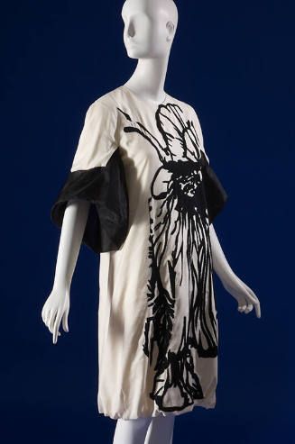 Off-white knee length dress with black abstract motif down entire front and ¾ length bell sleev…