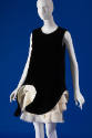 Black sleeveless above the knee shift dress with sculpted hem revealing tiered ivory underskirt