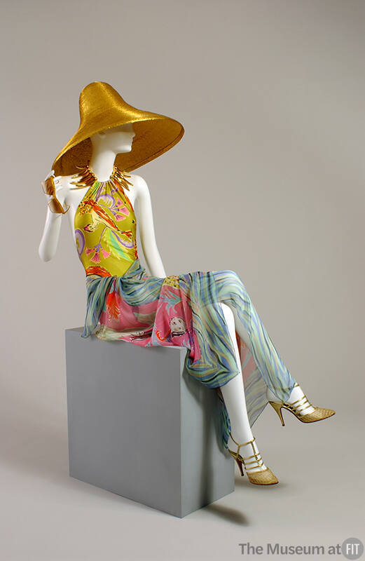 Gold straw sun hat, yellow floral bathing suit, blue multicolor sarong, gold strappy high heel …