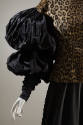 Detail view of leopard print top showing black taffeta sleeves of an oversize puff at upper arm…