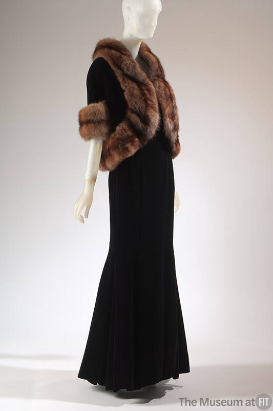 Black floor length evening dress and matching jacket with elbow length sleeves and brown fur tr…