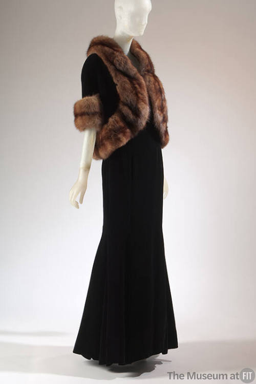 Black floor length evening dress and matching jacket with elbow length sleeves and brown fur tr…