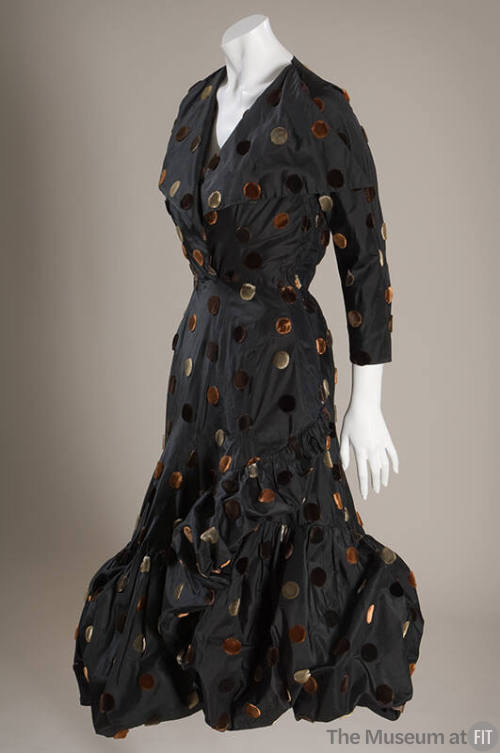 Black cocktail dress with large grey, tan and brown velvet dots, 7/8 length sleeves and asymmet…