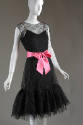 Sleeveless black net lace dress with round neck and scalloped hem ruffle over black slip with p…