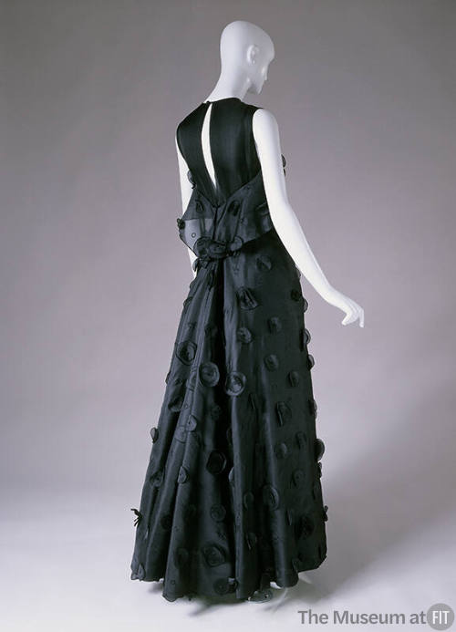 Back view of sleeveless black floor length dress with embroidered and applied circles on full s…