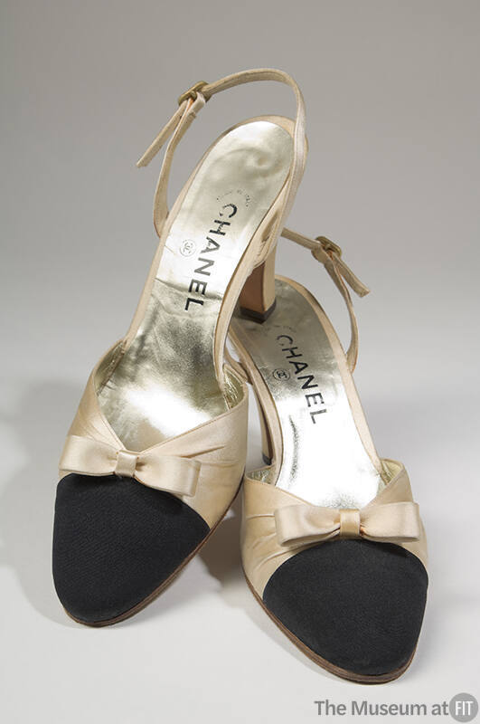 Pair of cream satin slingback shoes with black toe cap, small bow on vamp, high heel and Chanel…