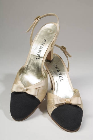 Pair of cream satin slingback shoes with black toe cap, small bow on vamp, high heel and Chanel…