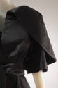 Detail of black cape with layered, folded large sleeve 