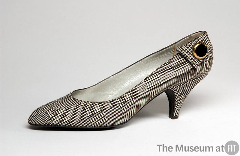 Single black and white plaid pump with large brass button at outer back heel
