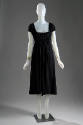 Black knee length dress with low, square neckline, cap sleeves and shirring at bodice
