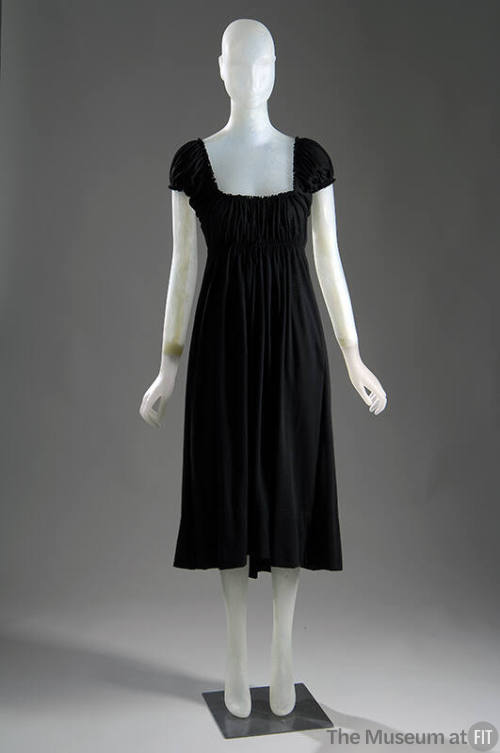 Black knee length dress with low, square neckline, cap sleeves and shirring at bodice
