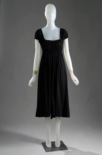Black knee length dress with low, square neckline, cap sleeves and shirring at bodice
