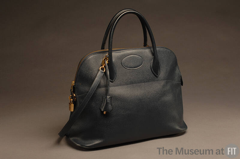 Black textured leather handbag with short handles, gold zipper and lock and shoulder strap 