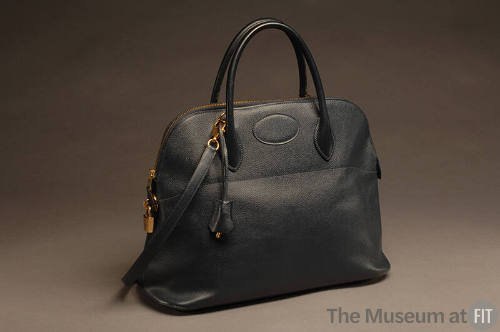 Black textured leather handbag with short handles, gold zipper and lock and shoulder strap 