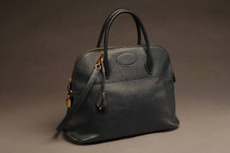 Black textured leather handbag with short handles, gold zipper and lock and shoulder strap 
