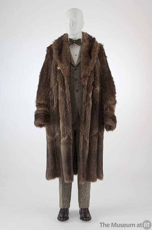 Brown raccoon fur calf length coat with wide lapels over black and white tweed suit with three …