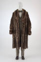 Brown raccoon fur calf length coat with wide lapels over black and white tweed suit with three …