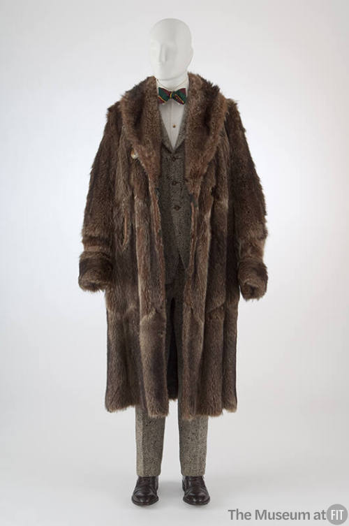 Brown raccoon fur calf length coat with wide lapels over black and white tweed suit with three …