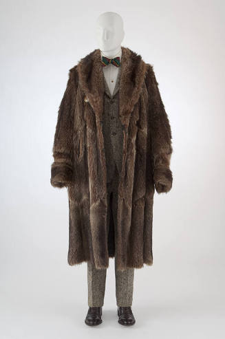 Brown raccoon fur calf length coat with wide lapels over black and white tweed suit with three …