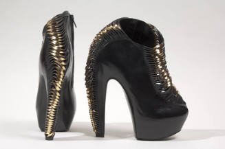 High black platform ankle boots with rows of horizontal strips twisting into gold metallic leat…