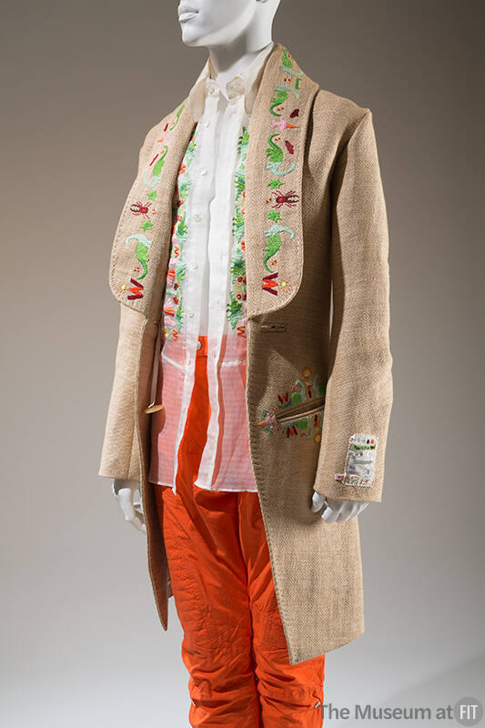 Beige animal embroidered long sleeve jacket, sheer white embroidered shirt and orange pants