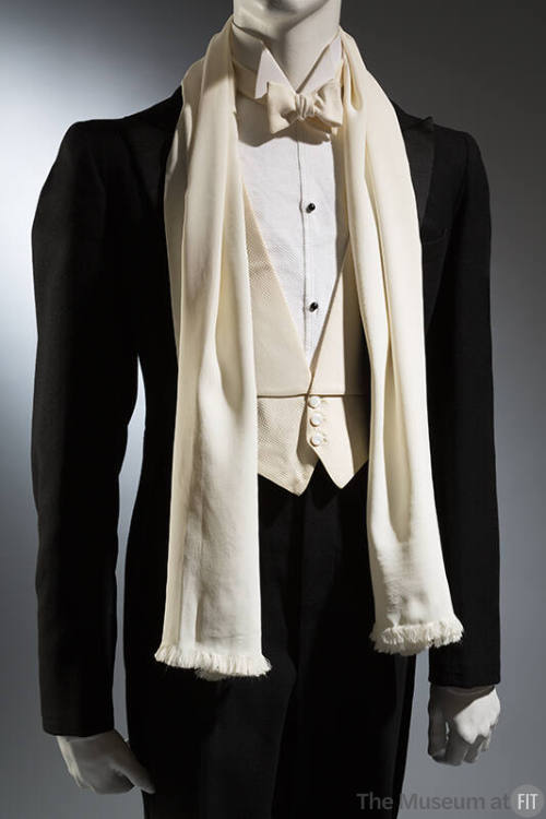 Detail of black tuxedo with off-white button front shirt, three button vest, bowtie and scarf