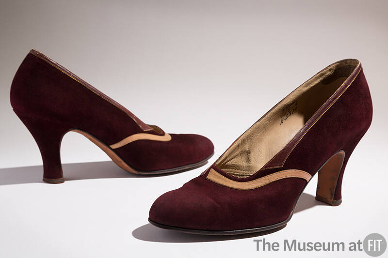 Pair of dark brown high heel pumps with tan leather band across vamp and brown leather band at …