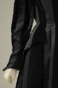 Close up of one long sleeve of a black coat made from alternating textured fabric