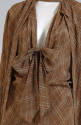 Close up of brown patterned dress self-tie bow at the bottom of low neck-line