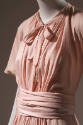 Pink dress with tie collar, front waist shirring, short bell sleeves, and sash tied at waist