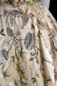 Detail view of cream evening dress showing wheat and floral embroidery of multicolor polychrome…