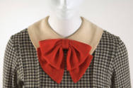Detail view of black and white check mini dress showing white Peter Pan collar with double red …