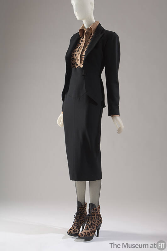 Black suit with fitted peplum jacket, narrow below-the-knee skirt, leopard pattern body suit an…